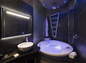 Mia Boutique Hotel في ميلانو: حمام مع حوض كبير ومغسلة