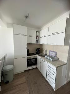Biała kuchnia z białymi szafkami i zlewem w obiekcie Apartments Meri w Dobrej Vodzie