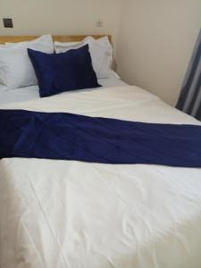 Una cama blanca con una almohada azul. en RÉSIDENCE MEUBLÉE CYMAT en Douala