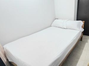 1 cama con sábanas blancas y almohadas en una habitación en Apartamento Loft amoblado Bucaramanga, en Bucaramanga