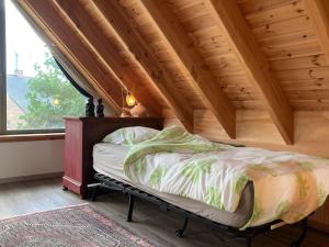 Cama en habitación con techo de madera en Gastenverblijf Chambre dAmis, en Heers