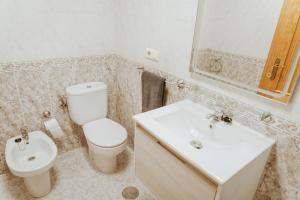 a white bathroom with a toilet and a sink at Picasso - Spacious Apartment in Old Town Nerja in Nerja +20 photos