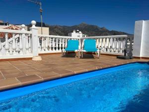 two blue chairs sitting next to a swimming pool at Picasso - Spacious Apartment in Old Town Nerja in Nerja