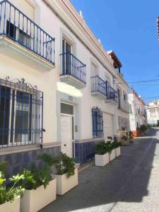 a white building with balconies and potted plants on a street at Picasso - Spacious Apartment in Old Town Nerja in Nerja