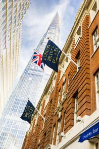 two british flags flying in front of a building at London Bridge Hotel in London