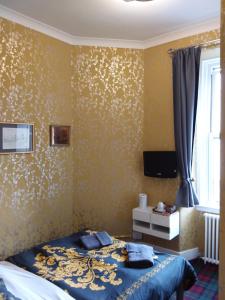 a bedroom with a bed and a yellow wall at IVY- Braveheart Guest House in Edinburgh