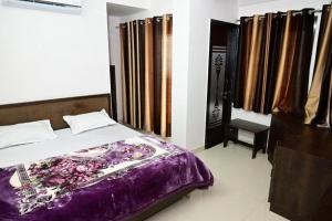 a bedroom with a bed with a purple blanket at Hotel Shree Chandram in Nāthdwāra