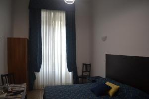 1 dormitorio con 1 cama y una ventana con cortinas azules en Incantoromano guest house, en Roma