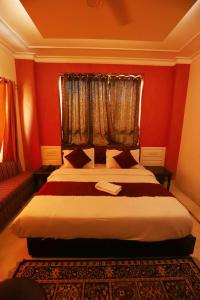 - une chambre avec un lit aux murs rouges et une fenêtre dans l'établissement Vagmi Inn, à Gurgaon
