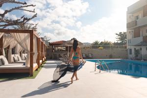 a woman in a bikini walking by a swimming pool at Dimitra Hotel & Apartments by Omilos Hotels in Kokkini Khanion