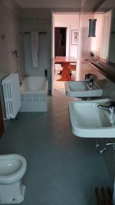 een badkamer met 3 wastafels, een toilet en een bad bij Villa Luigia in Leggiuno