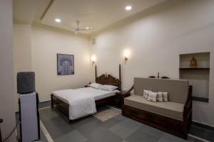 a bedroom with a bed and a couch and a tv at Heart of the City Homestay by Rashmi in Jaipur