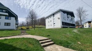 a large white building on a grassy hill with a house at Apartman Filipčić in Plitvička Jezera