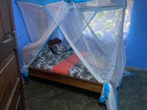 een klein bed met een baldakijn in een kamer bij Village Hostel in Nungwi