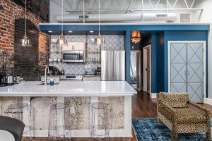 een keuken met blauwe muren en een aanrecht met krukken bij 80 Lex 203 Eclectic Industrial Apt in Asheville