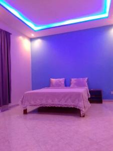 um quarto com uma cama com um tecto roxo em Villa Fama em Mbour