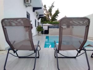 duas cadeiras sentadas ao lado de uma piscina em Villa Fama em Mbour