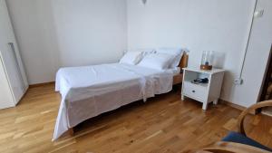 una camera da letto con un letto con lenzuola bianche e un comodino di Seafront Vacation home "Tea" a Trpanj (Trappano)