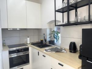 a kitchen with white cabinets and a sink and a stove at URBAN APARTMENTS PREMIUM No 12A, Free Parking, Self Check-in in Chorzów +15 photos
