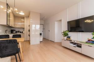 eine Küche und ein Esszimmer mit weißen Schränken und einem Holztisch in der Unterkunft Doki - Luxury Voyager by Grand Apartments in Danzig