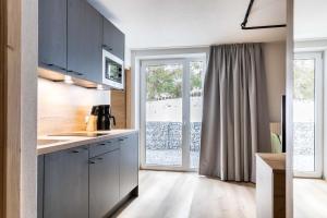 a kitchen with blue cabinets and a large window at Landhaus Bergland in Obsteig