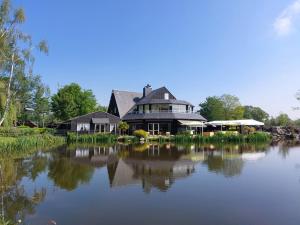 uma grande casa sentada em cima de um lago em Le Domaine du Cerf Blanc em Carentoir