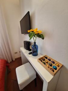 escritorio con un jarrón de flores y TV en b&b antichi colori, en Cinisi