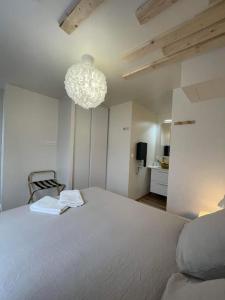 sypialnia z dużym białym łóżkiem i żyrandolem w obiekcie Luxueux T2 lumineux unique Saint Claude w mieście Saint-Claude