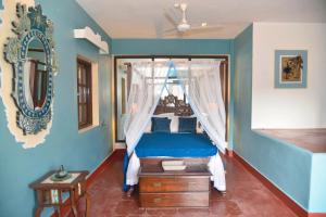 - une chambre avec un lit à baldaquin et des murs bleus dans l'établissement Casa Fontainhas, à Panaji