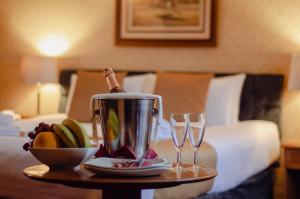 Howfield Manor Hotel في كانتربيري: طاولة مع كأسين من النبيذ وصينية من الفاكهة