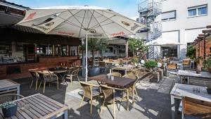 ein Restaurant im Freien mit Tischen, Stühlen und einem Sonnenschirm in der Unterkunft Hotel Haus Union in Oberhausen