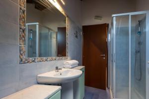 een badkamer met een wastafel en een douche met een spiegel bij Dante's Skyview - Appartamento mansarda Novara STAZIONE in Novara