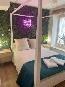 een slaapkamer met een bed met een bord aan de muur bij Cosy Jungle Room, évadez vous à Saint Claude in Saint-Claude