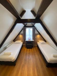 two beds in a attic room with a window at Hotel Old Quarter in Amsterdam