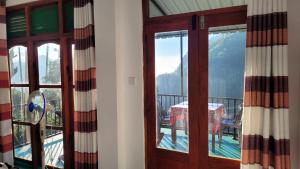 a door with a view of a table on a balcony at Chamodya Home Stay in Ella