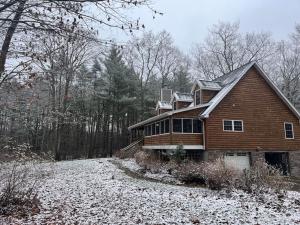 une maison dans les bois avec de la neige au sol dans l'établissement Discover Spring Haven in a Cozy Cabin Catskills, à Palenville
