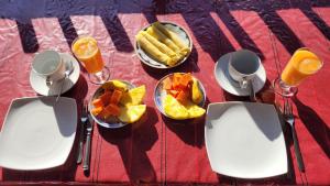 a table with a plate of food and glasses of orange juice at Chamodya Home Stay in Ella