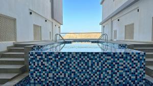 a swimming pool with a blue and black tile floor at Elegant 3-Bed room Sea-View in Muscat