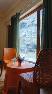 uma mesa e cadeiras num quarto com uma janela em Rivulet Resort & Camping em Mussoorie