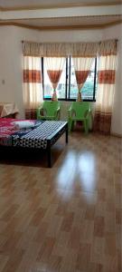 a bedroom with a bed and two chairs and windows at Cody Homestay in Burgos