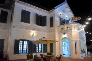 Monsane villa في لوانغ برابانغ: مبنى ابيض بطاوله ومظله