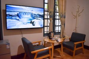 a living room with two chairs and a tv on the wall at Monsane villa in Luang Prabang