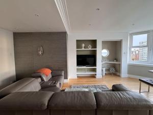 a living room with a couch and a television at Beautiful Penthouse By Seafront in Brighton & Hove