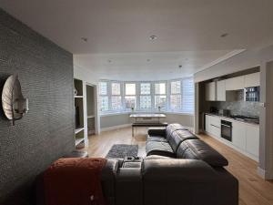 a living room with a leather couch and a kitchen at Beautiful Penthouse By Seafront in Brighton & Hove