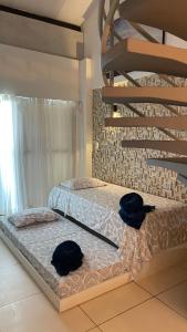 2 Betten in einem Zimmer mit zwei schwarzen Hüten darauf in der Unterkunft Laguna Beach Flat in Porto De Galinhas