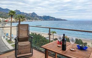 una mesa con copas de vino y una silla en el balcón en Awesome Apartment In Giardini Naxos With Wifi, en Giardini Naxos