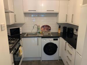 uma cozinha com uma máquina de lavar roupa e um lavatório em 1 bed Flat Service Apartment Beckenham em Beckenham