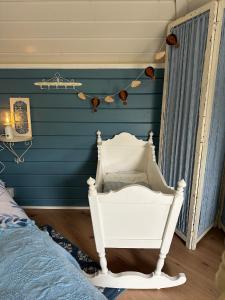 a bedroom with a blue wall with a white chair at B&B Cosy Garden in Alblasserdam
