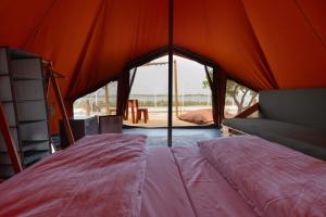 Schlafzimmer mit einem orangefarbenen Zelt und einem Bett in der Unterkunft Glamping Camp Faro in Faro