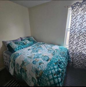 - une chambre avec un lit doté d'une couette bleue et d'une fenêtre dans l'établissement Room K Divine Villa and Resorts 5mins to EWR Airport and 4mins to Penn Station Newark, New York, à Newark